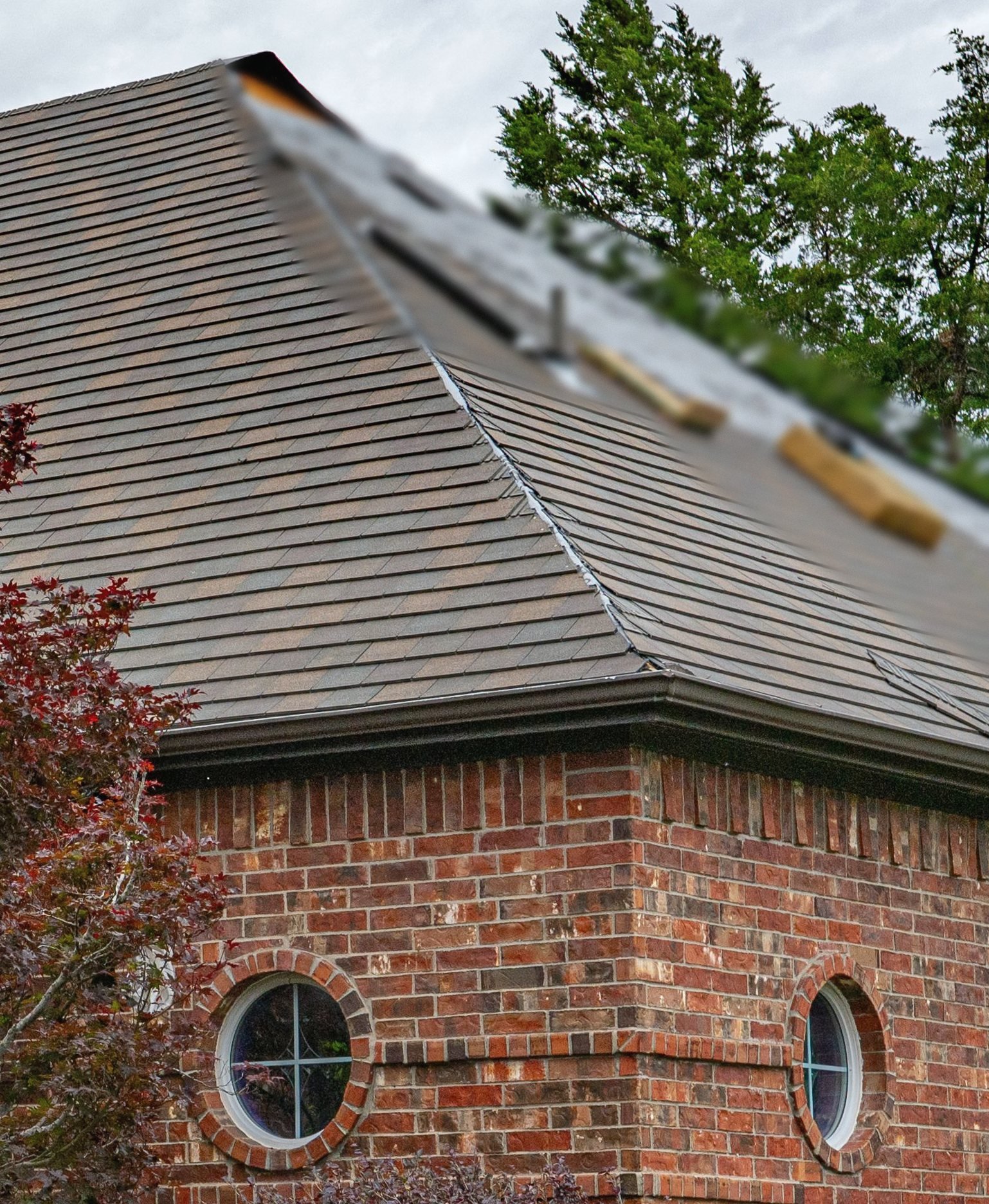 A hip roof mid-replacement: fresh shingle courses laid partway up, underlayment above, bundles staged